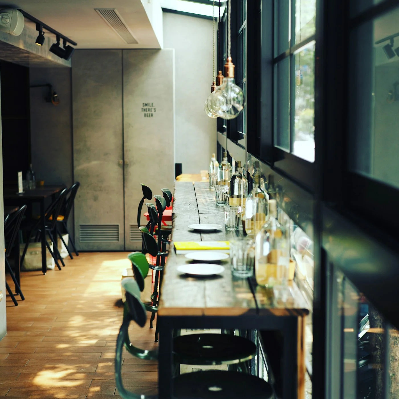 Window-side restaurant counter with green metal stools and adjacent dining chairs