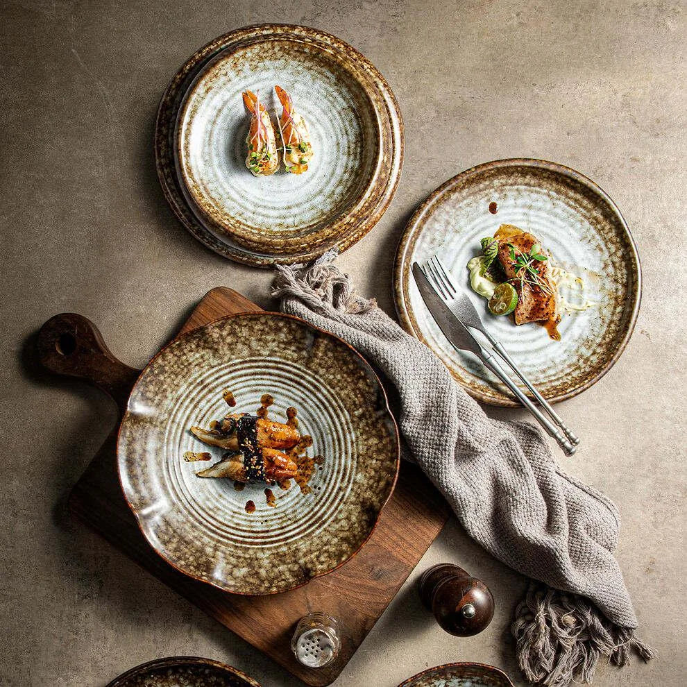 Three individually plated dishes on pale textured ceramic plates with dark brown rims, viewed from above.