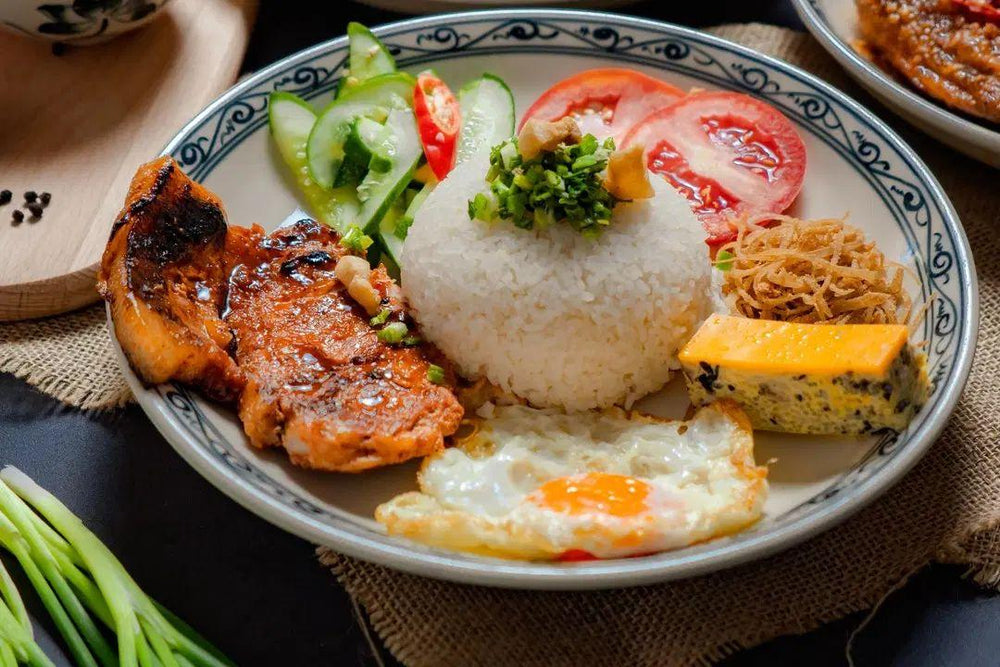Cơm tấm with rice, grilled pork, egg, pickles and accompaniments arranged across the usable plate surface.