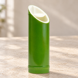 Green bamboo-shaped plastic sake bottle on a neutral tabletop, empty contextual view