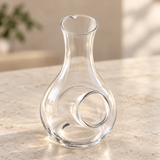 Clear glass sake bottle with side cooling pocket on a neutral tabletop, empty contextual view