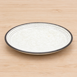 K275-PE ivory round plate with dark rim on a light wood table
