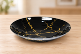 K590-LIT1 black and gold deep ceramic plate on a light wood table