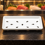 KM5924 white porcelain sushi case plate on a sushi-bar counter beside a display case