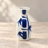 White sake bottle with blue bamboo motif on a neutral tabletop, empty contextual view
