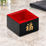 OMS-6 black and red sake masu cup with gold 福 character on a pale restaurant table