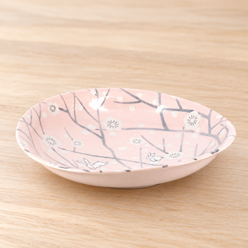 Pink rabbit and blossom plate on a light wood tabletop