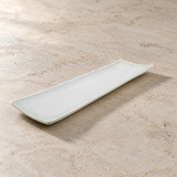 Long white rectangular platter with subtle pale border on a neutral stone tabletop, empty contextual view