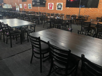 Black metal restaurant chair with black padded seat; restaurant setting with other furniture illustrative