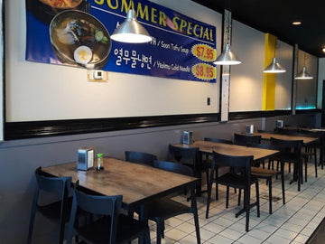 Black open-back plastic restaurant chair; restaurant setting, other furniture illustrative