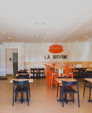Black open-back plastic restaurant chair; restaurant setting, other furniture illustrative