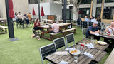 Black Stackable Indoor/Outdoor Chair with Silver Aluminum Frame in a restaurant setting; other furniture is illustrative