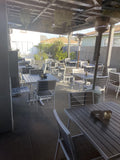 Black Stackable Indoor/Outdoor Chair with Silver Aluminum Frame in a restaurant setting; other furniture is illustrative