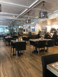 Black Upholstered Restaurant Chair with Stainless Steel Legs in a restaurant setting; other furniture is illustrative