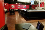 Black Vinyl Restaurant Chair with Walnut-Finish Metal Frame in a restaurant setting; other furniture is illustrative