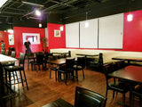 Black Vinyl Restaurant Chair with Walnut-Finish Metal Frame in a restaurant setting; other furniture is illustrative
