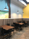 Black Vinyl Restaurant Chair with Walnut-Finish Metal Frame in a restaurant setting; other furniture is illustrative