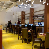 Brown Upholstered Restaurant Chair with Walnut-Finish Metal Frame in a restaurant setting; other furniture is illustrative