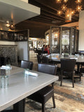 Brown Upholstered Restaurant Chair with Walnut-Finish Metal Frame in a restaurant setting; other furniture is illustrative