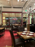 Brown Upholstered Restaurant Chair with Walnut-Finish Metal Frame in a restaurant setting; other furniture is illustrative