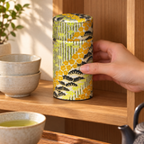 Closed botanical washi tea canister being placed on a tea shelf