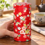 Tall red floral tea container in a table setting. Contextual accessories are not included.