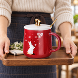 Red rabbit mug with white lid, gold-tone knob and spoon in a carrying setting. Contextual accessories are not included.