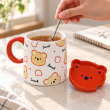 White bear mug with red lid and spoon in a stirring setting. Contextual accessories are not included.