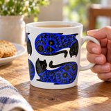 Blue-and-black cat mug in a table setting. Contextual accessories are not included.