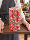 Red ribbon-and-blossom tea container in a carrying setting. Contextual accessories are not included.