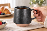 RT72-3 charcoal mug held by its handle; breakfast food is contextual.