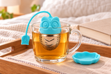 Blue owl infuser steeping in a clear mug with matching tray alongside