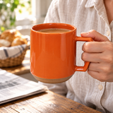 Orange C011 ceramic mug held with coffee at breakfast