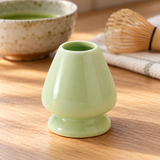 Pale green G-1763 ceramic whisk holder beside matcha preparation accessories