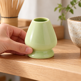 Pale green G-1763 ceramic whisk holder being placed on a tea shelf