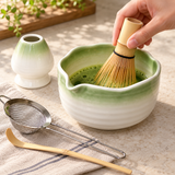 Green-rimmed matcha set during whisking with scoop, strainer and whisk holder alongside