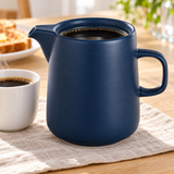 Navy ceramic coffee server at a breakfast table beside a cup