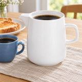 White ceramic coffee server at breakfast beside a blue cup