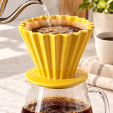 Yellow fluted ceramic coffee dripper brewing into a glass server