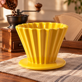 Yellow fluted ceramic coffee dripper beside a coffee grinder being filled