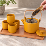Yellow tea set with four cups during loose-leaf preparation