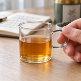 Small JN080-MM glass mug held by its handle during tea tasting