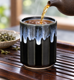 Tea being poured into the black and pale-blue drip-glaze teacup