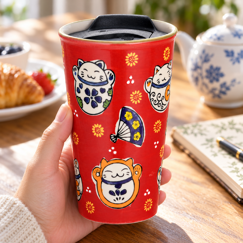 Red lucky-cat tumbler held during a breakfast break