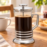 Four-cup chrome and glass press with brewed coffee at breakfast