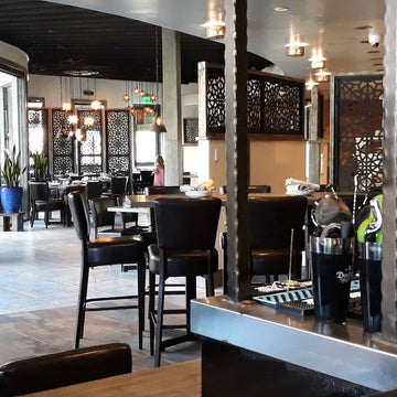 Dark Brown Upholstered Restaurant Barstool with Wood-Grain Metal Frame in a restaurant setting; other furniture is illustrative