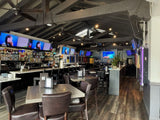 Dark Brown Upholstered Restaurant Barstool with Wood-Grain Metal Frame in a restaurant setting; other furniture is illustrative