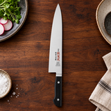 IKKAKU Donryu 210 mm gyuto in a dark kitchen preparation setting