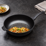 12.5" (32 cm) Diamond Nonstick Cast Aluminum Wok Pan with a finished food preparation on a restaurant counter