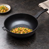 13.5" (34 cm) Diamond Nonstick Cast Aluminum Wok Pan with a finished food preparation on a restaurant counter
